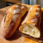Two golden brown loaves of homemade french bread, one whole and one sliced open showing the airy interior crumb.