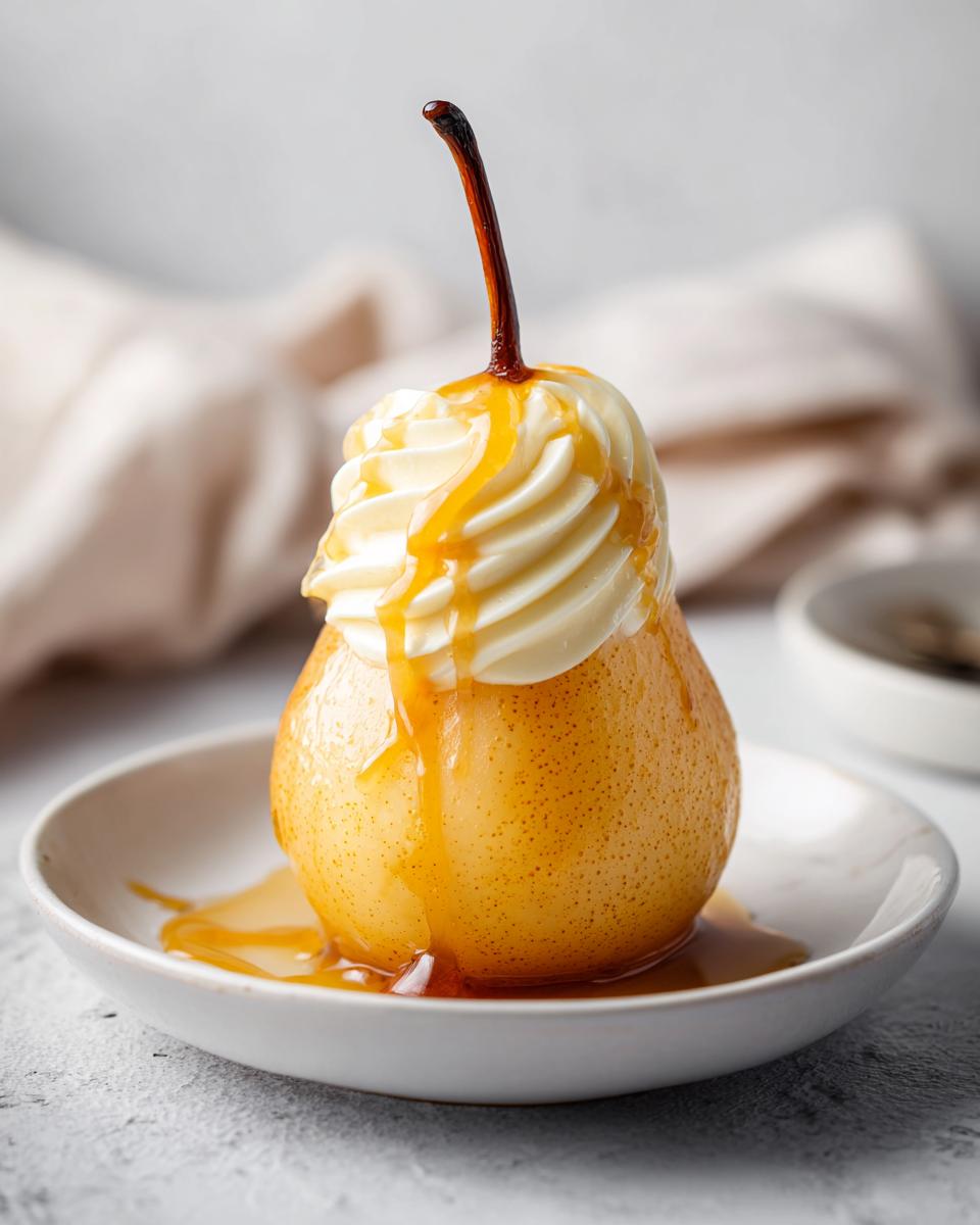 A perfectly cooked poached pear topped with piped whipped cream and drizzled with caramel sauce.