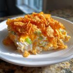 A scoop of creamy hot chicken salad topped generously with melted cheese and crunchy corn flakes.