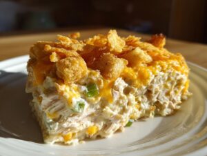 A generous slice of creamy hot chicken salad topped with melted cheese and crunchy cornflakes.