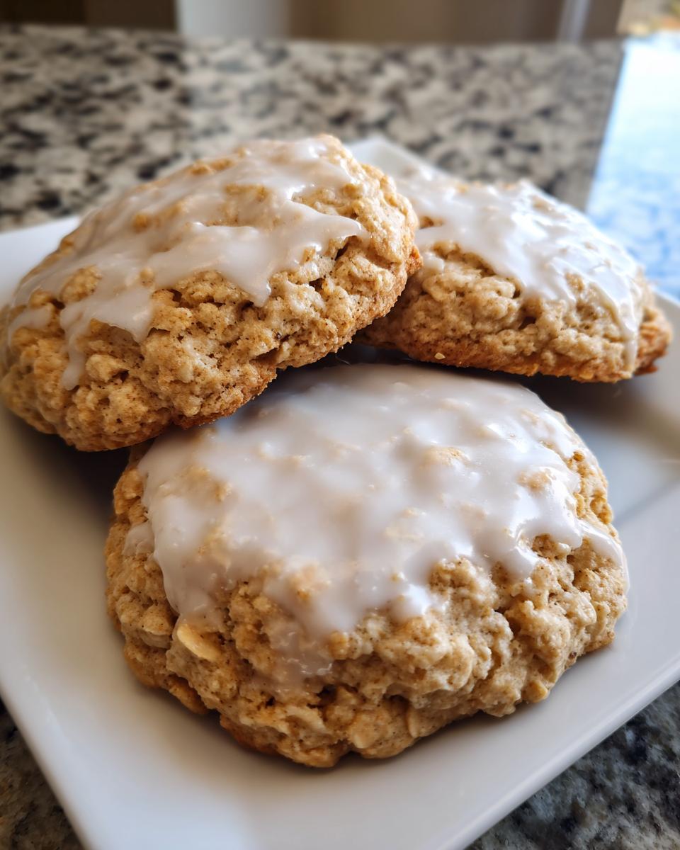 Close-up of three soft, textured iced oatmeal cookies topped with thick white glaze.