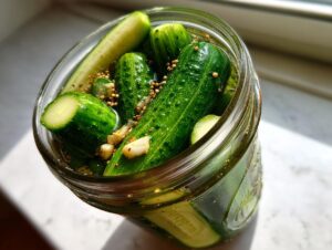 Close-up overhead view of fresh cucumbers soaking in brine with garlic and mustard seeds for refrigerator pickles.