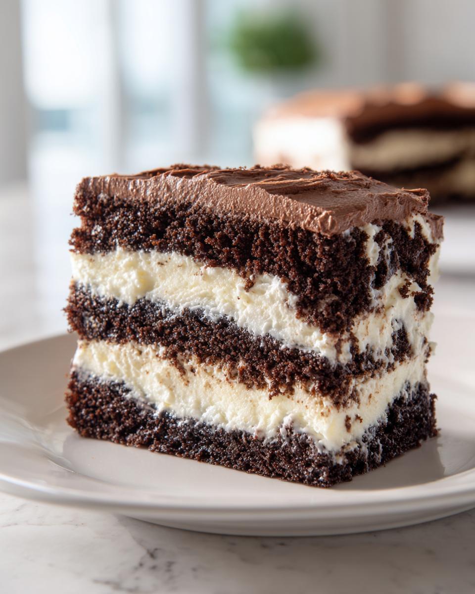 A tall slice of layered chocolate cake with white cream filling, resembling an italian love cake, topped with chocolate frosting.