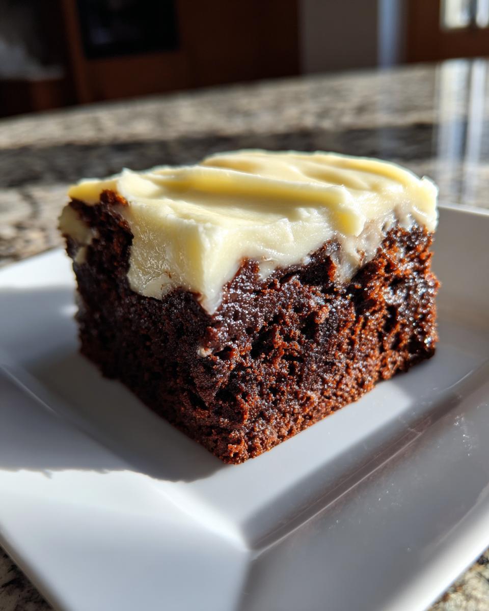 A close-up of a square gingerbread brownies slice topped with thick, creamy white frosting.