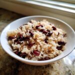 Close-up of a white bowl filled with fluffy rice mixed with dark red kidney beans, featuring amazing black beans and rice flavor.