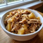 Close-up of a white bowl filled with shredded pork and sauerkraut, showing tender meat and soft cooked cabbage.