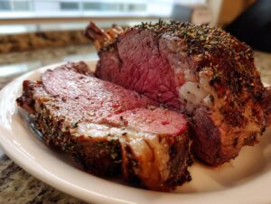Close-up of a perfectly cooked prime rib recipe roast, sliced to show a medium-rare pink center and herb crust.