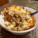 Close-up of a spoonful of fluffy french onion butter rice showing caramelized onions and a crispy top layer.