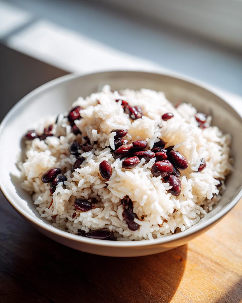Close-up of a white bowl filled with fluffy white rice mixed with dark red kidney beans, representing black beans and rice.