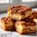 A stack of three moist snickerdoodle blondies featuring a thick, sugary cinnamon topping and swirl.