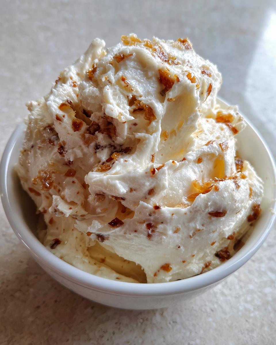 Close-up of creamy, whipped onion dip topped generously with caramelized onion pieces.