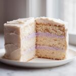 Cross-section view of a slice of amazing lavender cake showing three layers of light sponge and two layers of purple filling.