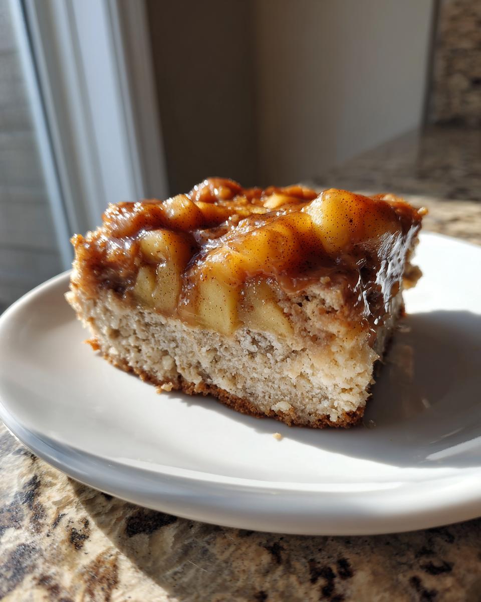 A close-up of one square slice of apple pie maple donut bars on a white plate.