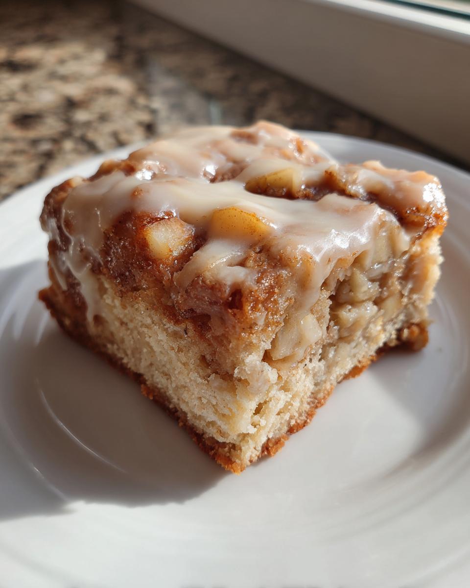 A close-up of one square of apple pie maple donut bars topped with thick white glaze.