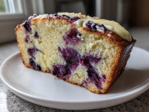 Close-up of a moist slice of Blueberry Cream Cheese Bread showing blueberries and cream cheese swirl.