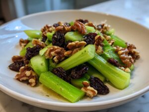 Close-up of a vibrant celery salad with walnuts and dates, lightly dressed in a white bowl.