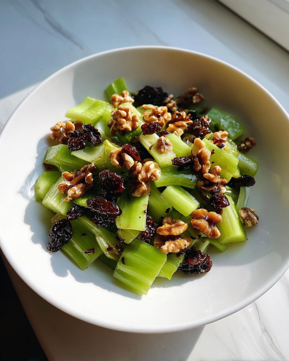 A white bowl filled with chopped celery, walnuts, and dried dates, showcasing the celery salad with walnuts and dates.