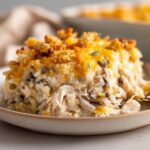 A close-up of a creamy portion of chicken wild rice casserole Paula Deen recipe topped with melted cheddar and crunchy stuffing.