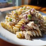 Close-up of a serving of creamy cold tuna pasta salad made with rotini pasta, tuna, red onion, and celery.