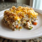 A close-up serving of creamy chicken wild rice casserole topped with melted cheddar cheese and breadcrumbs.