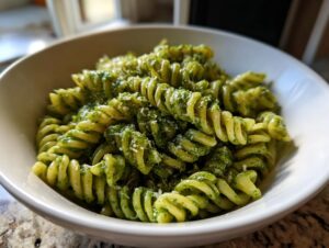 Close-up of creamy pesto pasta made with fusilli noodles, topped with grated cheese.