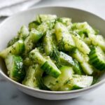 Close-up of a bowl filled with chopped cucumber celery salad tossed in a light dressing and fresh dill.
