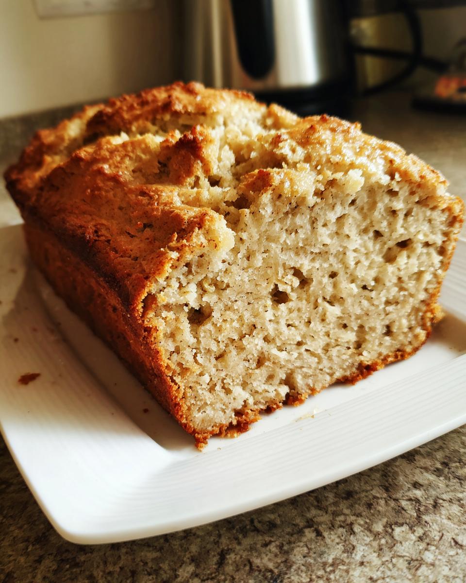 Close-up of a golden-brown loaf of gluten free beer bread sliced open, showing a moist, porous crumb.