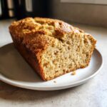 A close-up of a freshly baked loaf of gluten free beer bread, sliced to show its moist, porous texture.