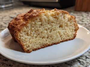 Close-up of a thick slice of golden brown gluten free beer bread showing its soft, airy crumb texture.