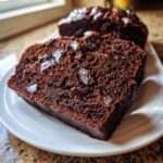 Close-up of moist slices of healthy chocolate banana bread studded with dark chocolate chips on a white plate.