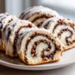Close-up of sliced italian nut roll cookies with a creamy white glaze and rich nut filling.