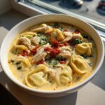 A close-up of a bowl of Marry Me Chicken Tortellini Soup, featuring tortellini, shredded chicken, and sun-dried tomatoes.