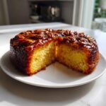 A slice cut from a pecan upside down cake with box cake mix, showing a moist yellow crumb and sticky pecan topping.