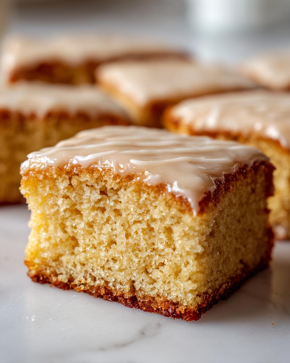 A close-up of a square piece of soft maple donut bars showing the fluffy texture and thick maple glaze topping.