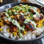 Close-up of a street corn chicken rice bowl featuring grilled chicken, corn, and creamy green sauce over white rice.