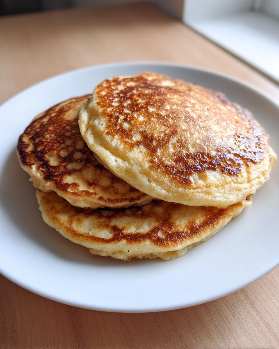 A stack of three golden-brown vegan sourdough discard pancakes on a white plate.