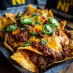 Close-up of a serving of walking frito pie loaded with chili, melted cheese, and sliced jalapeños.