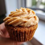 Close-up of a moist banana cupcake topped with richly swirled cinnamon frosting.