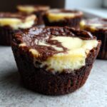 A close-up of one decadent brownie cheesecake cup showing the dark chocolate base and swirled cream cheese topping.