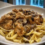 Close-up of creamy chicken marsala pasta featuring tender chicken pieces and sautéed mushrooms over fettuccine noodles.