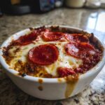 Close-up of a baked cottage cheese pizza bowl topped with melted mozzarella and pepperoni slices.