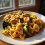 Close-up of cowboy butter lemon bowtie chicken pasta mixed with bright green broccoli florets in a creamy sauce.