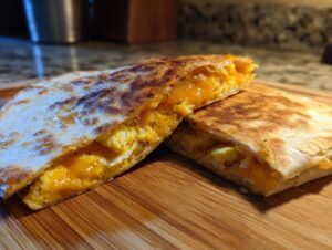 Two halves of a perfectly golden fried egg quesadilla filled with melted cheese and scrambled eggs.