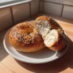 Close-up of a sliced greek yogurt protein bagel showing its fluffy, white interior and everything bagel seasoning.