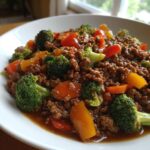 Close-up of a savory ground beef stir fry mixed with bright green broccoli florets and colorful bell peppers in a rich sauce.