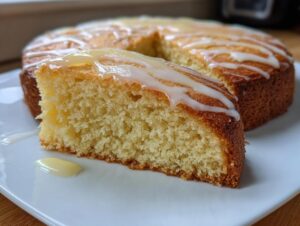 A close-up of a moist slice cut from a healthy greek yogurt cake, topped with a white glaze drizzle.