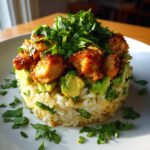 A beautifully plated honey lime chicken & avocado rice stack, topped with glazed chicken pieces and fresh cilantro.