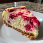 Close-up of a perfect slice of no bake lemon raspberry cheesecake showing the creamy filling and graham cracker crust.