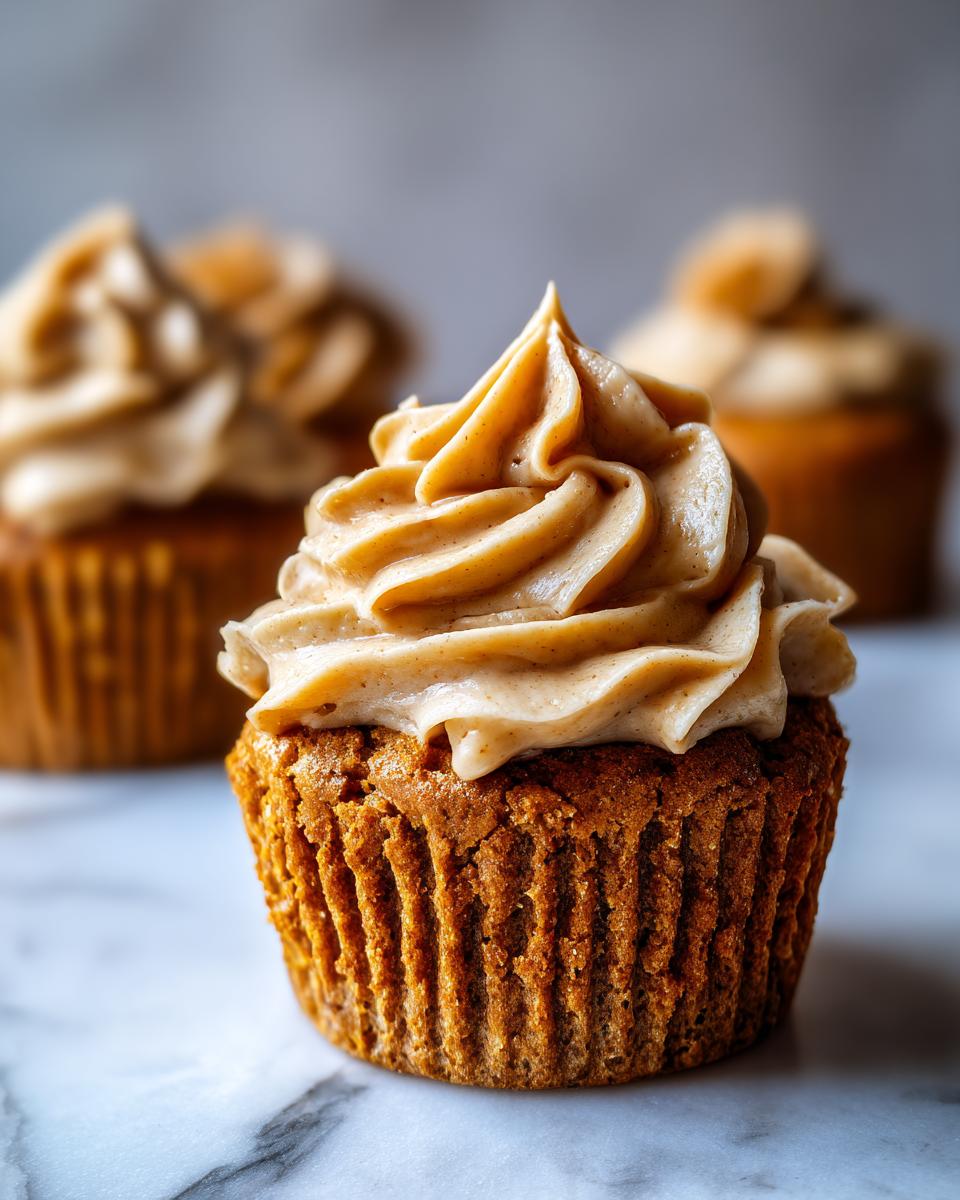 A close-up of one perfectly baked peanut butter banana cupcake topped with swirled peanut butter frosting.