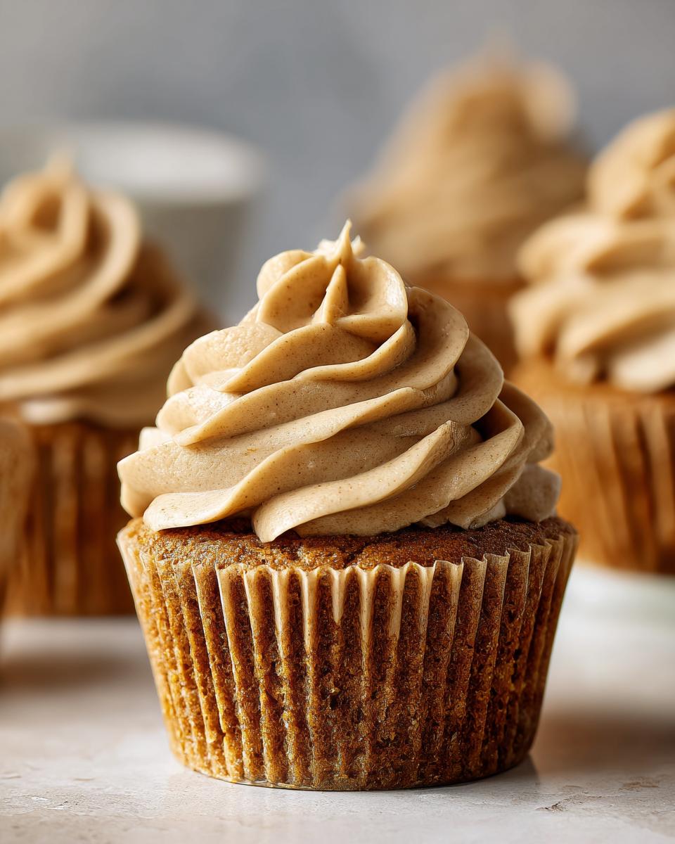 A close-up of one perfectly baked peanut butter banana cupcake topped with a swirl of light brown peanut butter frosting.